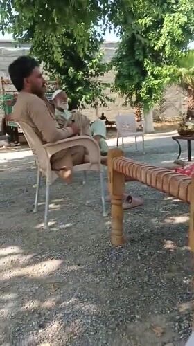 Daytime gathering recorded in Pakistani yard with furniture, people