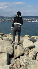 Woman walks rocky shoreline in Varna, Bulgaria