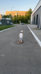 Toddler plays outdoors, offers grass to adult in Kazan