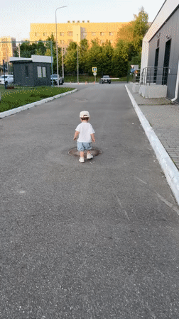 Toddler plays outdoors, offers grass to adult in Kazan