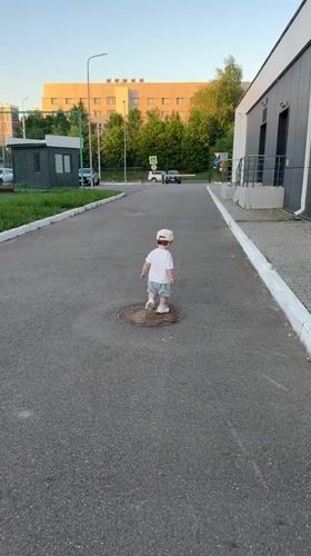Toddler plays outdoors, offers grass to adult in Kazan