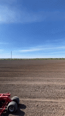 Farm equipment operates in field during spring planting season