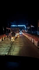 Night traffic crosses metal bridge in Blang Mee, Indonesia