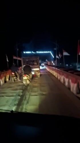 Night traffic crosses metal bridge in Blang Mee, Indonesia
