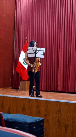 Woman performs saxophone on wooden stage in Arequipa