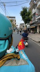 Moped rider carries Vietnamese flag through Thủ Đức