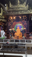 Visitor documents Buddhist shrine statues and offerings in Thailand