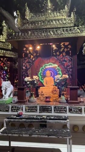 Visitor documents Buddhist shrine statues and offerings in Thailand