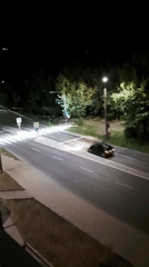 Nighttime city intersection, green light, car moving through