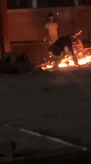 Two people tend small bonfire in Jos, Nigeria