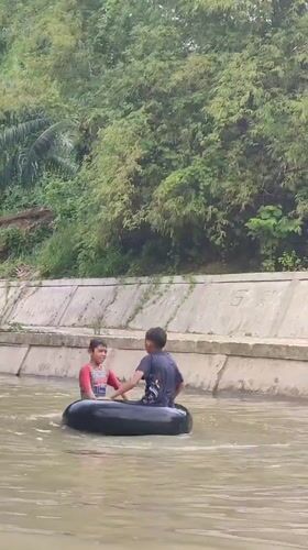 Boys enjoy river tubing in Saweuk, Indonesia