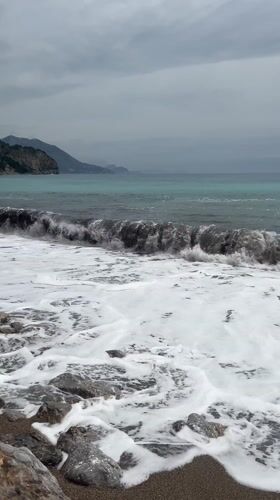 Waves crash on rocky Montenegro beach under cloudy skies