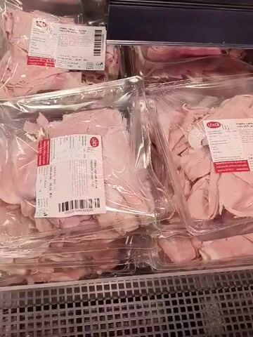 The video captures a close-up view of several packages of sliced deli ham displayed in a refrigerated section of what appears to be a grocery store or supermarket in Jesenice, Czechia.

The primary subjects are multiple plastic containers holding thinly sliced, light pink ham. Each package is sealed and features a label with product information and a barcode. The camera moves slightly, panning across the packages, suggesting a person is walking past or examining the products.

Visible text on the labels includes the brand name "LE&CO." Czech text identifies the product as "Plátky nářezák šunka nejvyšší jakosti" (Sliced ham of the highest quality). Pricing details are also displayed: "Cena za kg: 69.90 Kč" (Price per kg: 69.90 CZK) and "Cena za ks: 31.00 Kč" (Price per piece: 31.00 CZK). A "Consume by" date, "23.06.2025," and recommended storage temperature of "2-5 °C" are also clearly visible. No people are seen in the video, and the time of day and weather are not discernible. The setting is clearly an indoor commercial environment.