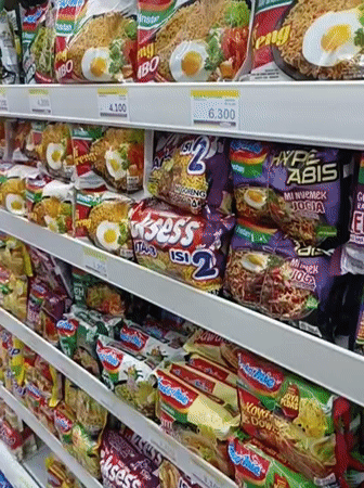 Inside a stocked Indonesian convenience store, snacks and bread on shelves