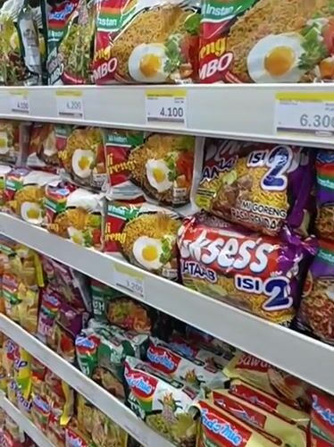 Inside a stocked Indonesian convenience store, snacks and bread on shelves