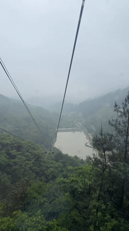 Cable car ascends through foggy mountains in Yongding District