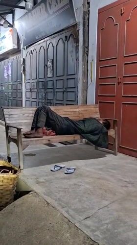 Person rests on wooden bench in Keudegeudong, Indonesia