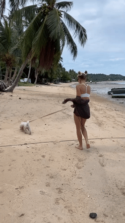 Woman walks dog on Thai beach during low tide morning