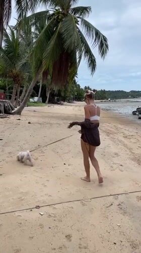 Woman walks dog on Thai beach during low tide morning