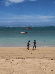 Two boys walk beach shoreline in Kute, Indonesia