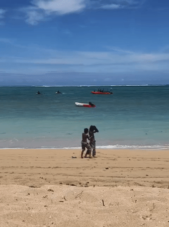 Two boys walk beach shoreline in Kute, Indonesia