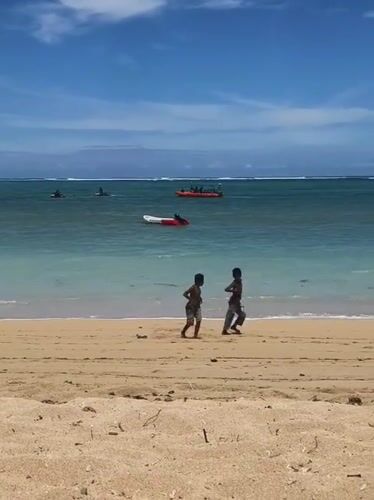 Two boys walk beach shoreline in Kute, Indonesia