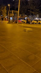 Skateboarders cruise through illuminated Barcelona plaza at night
