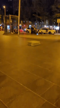 Skateboarders cruise through illuminated Barcelona plaza at night