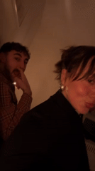 Woman in black turtleneck observed in dimly lit London room