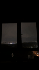 Nighttime cityscape observed through window shows illuminated streets