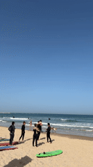 Six wetsuit-clad beachgoers gather at Tel Aviv beach