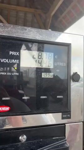 The video shows a close-up of a gas pump display. The display shows the price as 29.13 Euros and the volume as 14.64 liters. The price per liter is 1.990 Euros. The camera then pans to show the different fuel options available at the pump, including Diesel, Excellium Diesel, Sans Plomb 95-E10, and Excellium Sans Plomb 98. There are cars visible in the background. The video is taken from the perspective of someone filling their car with gas.