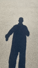 Person's shadow captured on paved surface during midday
