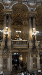 Visitors explore ornate Palais Garnier opera house interior in Paris