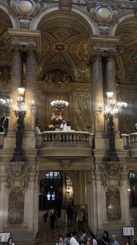 Visitors explore ornate Palais Garnier opera house interior in Paris