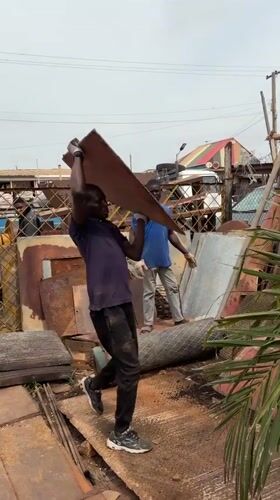 Workers load scrap metal at Nigerian recycling facility