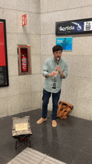 Street musician plays clarinet in subway station amid urban scenes
