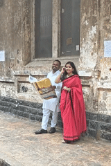 Couple reads newspaper on Mumbai sidewalk