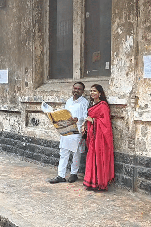 Couple reads newspaper on Mumbai sidewalk