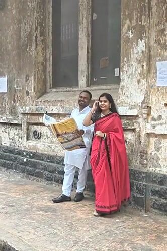 Couple reads newspaper on Mumbai sidewalk