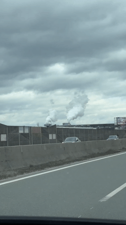 Motorist films industrial smokestacks from highway near Wals, Austria