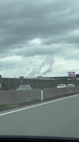 Motorist films industrial smokestacks from highway near Wals, Austria