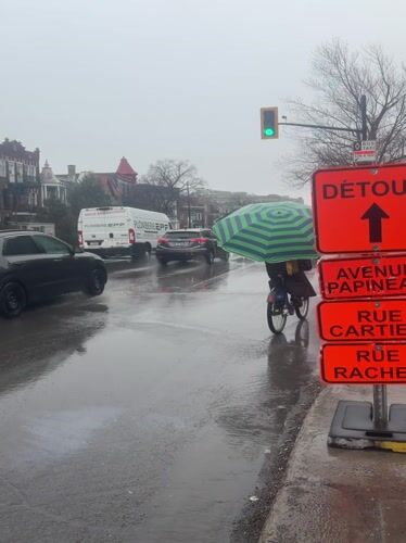 Cyclist uses umbrella while riding through rainy Montreal streets