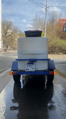 Red tractor pulls tank trailer through wet Moscow streets