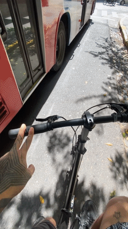 Cyclist rides through Buenos Aires street alongside red bus