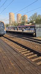 Passenger train arrives at Khimki station, witnessed by platform observers