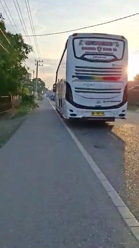 White bus parked on quiet Indonesian road at sunrise