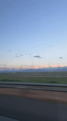Dawn or dusk illuminates snow-capped mountains near Russian highway
