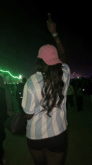 Person in striped shirt, pink cap walks through Indio crowd