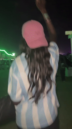 Person in striped shirt, pink cap walks through Indio crowd